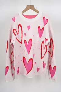 Detailed view of a pink oversized knit sweater featuring a vibrant red heart pattern.