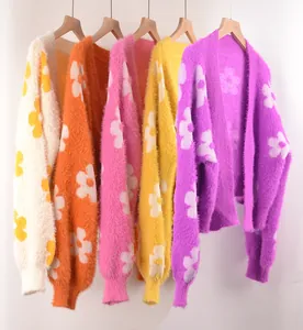 Primer plano de cárdigans de mohair coloridos con motivos florales en blanco, naranja y rosa.