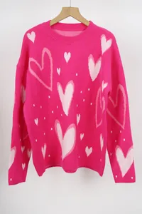 Close-up of bright pink women's knit sweater with cute white heart patterns all over.