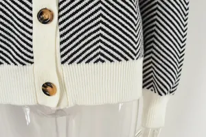 Macro detail of black and white chevron knit cardigan with stylish tortoise buttons