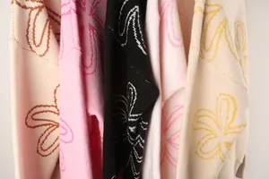 Close-up of colorful knitted sweaters with oversized floral patterns in multiple colors