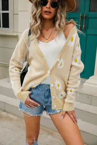 Detailed view of women's yellow knit cardigan featuring white daisy print and buttons