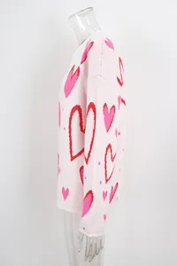 Side profile detail of pink women's knit sweater featuring red and pink heart patterns.