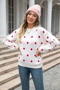 Outdoor street shot of a woman wearing a white polka dot knit sweater and pink beanie.