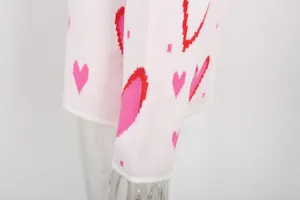Close-up detail of soft pink knit sweater featuring vibrant red heart patterns.