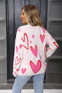 Detailed back view of a loose pink knit sweater featuring red and pink heart patterns