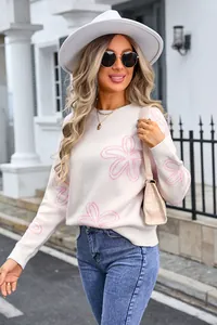 Close-up of elegant white knit sweater featuring pink floral patterns on a model