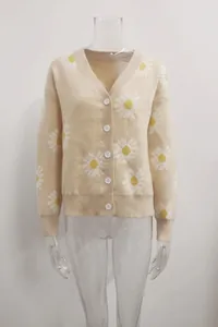 Detail of a beige knit cardigan featuring a cheerful white and yellow daisy floral print
