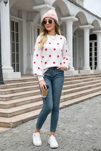 Stylish white pullover knit sweater with red polka dots worn with blue jeans outdoors