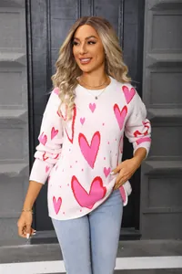 Lifestyle shot of a oversized pink sweater with red heart patterns on a model