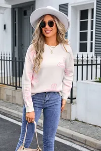 Detailed view of women's white round neck knitted sweater with pink floral pattern