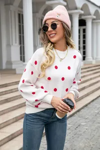 Close-up of woman wearing a stylish white knit sweater with large red polka dots outdoors