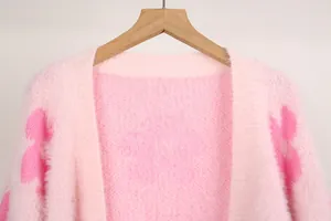 Vista detallada de la textura de punto rosa suave y el patrón floral de la chaqueta