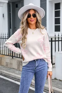 Detailed view of women's white long sleeve sweater with pink floral outlines and soft knit texture