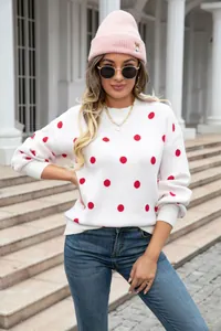Close-up detail showing the texture and red polka dot pattern of the white sweater