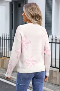 Detailed back view of a cream knitted sweater featuring elegant pink floral patterns