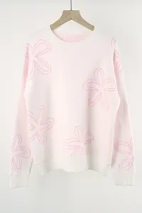 Close-up of a cream knit sweater featuring pink floral outlines on a wooden hanger