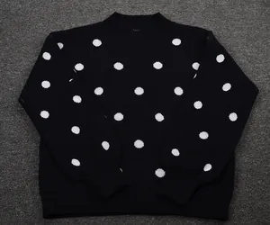 Close-up of black knitted sweater with white polka dot pattern and ribbed crew neck