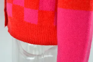 Close-up detail of a pink and red checkered knit cardigan showing fabric texture.