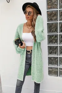 Model wearing a green chevron knit cardigan over a white crop top and dark grey denim.