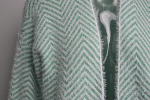 Macro detail of the soft green and white chevron patterned fuzzy knit cardigan fabric