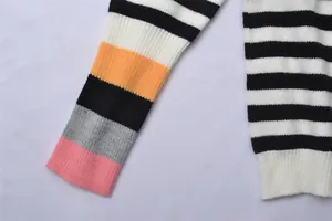 Gros plan de la manche et de l'ourlet d'un pull en maille rayé aux détails colorés.