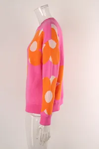 Side view of pink knit sweater featuring large orange and white floral patterns.