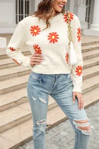 Close-up of a stylish cream knit sweater featuring vibrant red daisy floral patterns.
