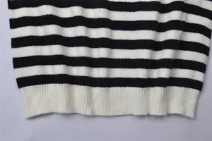 Gros plan sur l'ourlet côtelé et les rayures noires et blanches d'un pull en maille douce