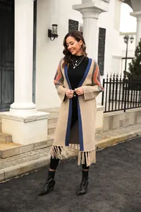 Full-length view of a long beige knit cardigan with blue trim and fringe details