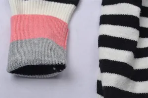 Détail rapproché de la manchette côtelée color-block et du tissu en maille rayée du pull