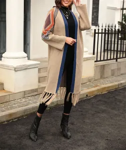 Long beige knit cardigan with colorful geometric patterns and fringe detail on woman