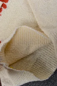 Close-up detail showing the soft knit texture and ribbed collar of daisy sweater