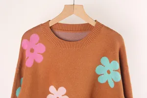 Close-up of crewneck knit sweater featuring colorful floral patterns on rust brown fabric
