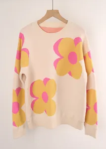 Detail of cream knitted sweater featuring vibrant pink and yellow flower patterns.