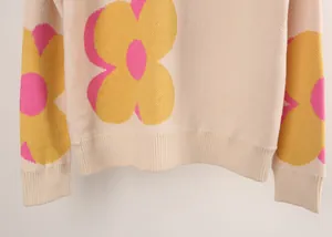 Detail of cream knitted sweater featuring large yellow and pink floral prints