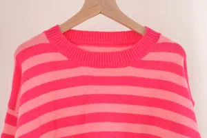 Détail de la texture en maille rayée rose et du col rond suspendu sur un cintre
