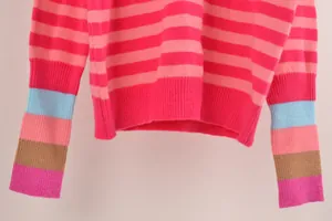 Gros plan d'un pull en maille rayé rose vif avec des détails de manches multicolores.