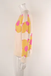 Detailed side view of cream knit sweater featuring bold yellow and pink floral print