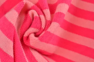 Détail macro d'un tissu tricoté à rayures roses et rouges montrant une texture douce.