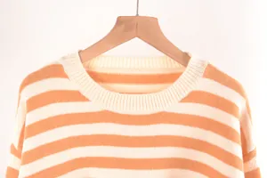 Gros plan du col rond côtelé sur un pull en maille rayé orange et blanc pour femme