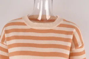 Gros plan sur le col rond doux d'un pull en maille à rayures orange et beige.