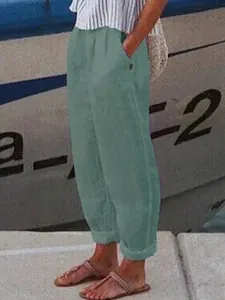 Detailopname van de comfortabele saliegroene vrijetijdsbroek met zijzakken op een model.