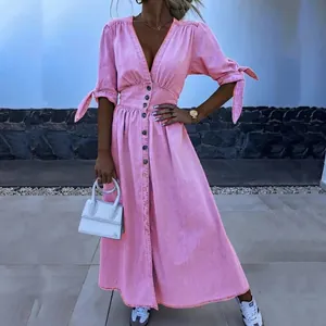Detail view of a pink button-down midi dress with waist tie and V-neckline.