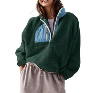 Detalle de jersey de forro polar sherpa verde oscuro con bolsillo y cremallera azul claro.