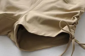 Detalle de pantalones cortos de yoga color caqui con cordón lateral y tejido elástico