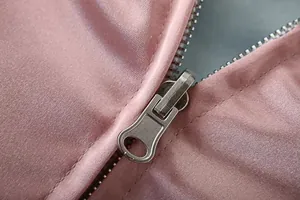 Nahaufnahme des silbernen Metallreißverschlusses an der rosa Satin-Sukajan-Jacke.