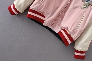 Detailansicht der Vogelbestickung und der gestreiften Bündchen einer rosa Bomberjacke