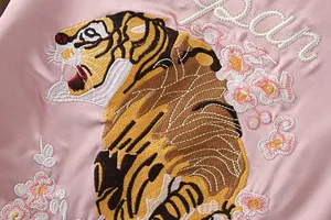Detaillierte Makroansicht der Tiger- und Kirschblütenstickerei auf rosa Satinjacke