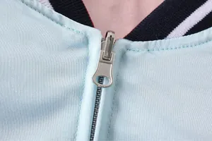 Makrodetail des glatten Metallreißverschlusses und des hellblauen Stoffes einer Wendejacke.